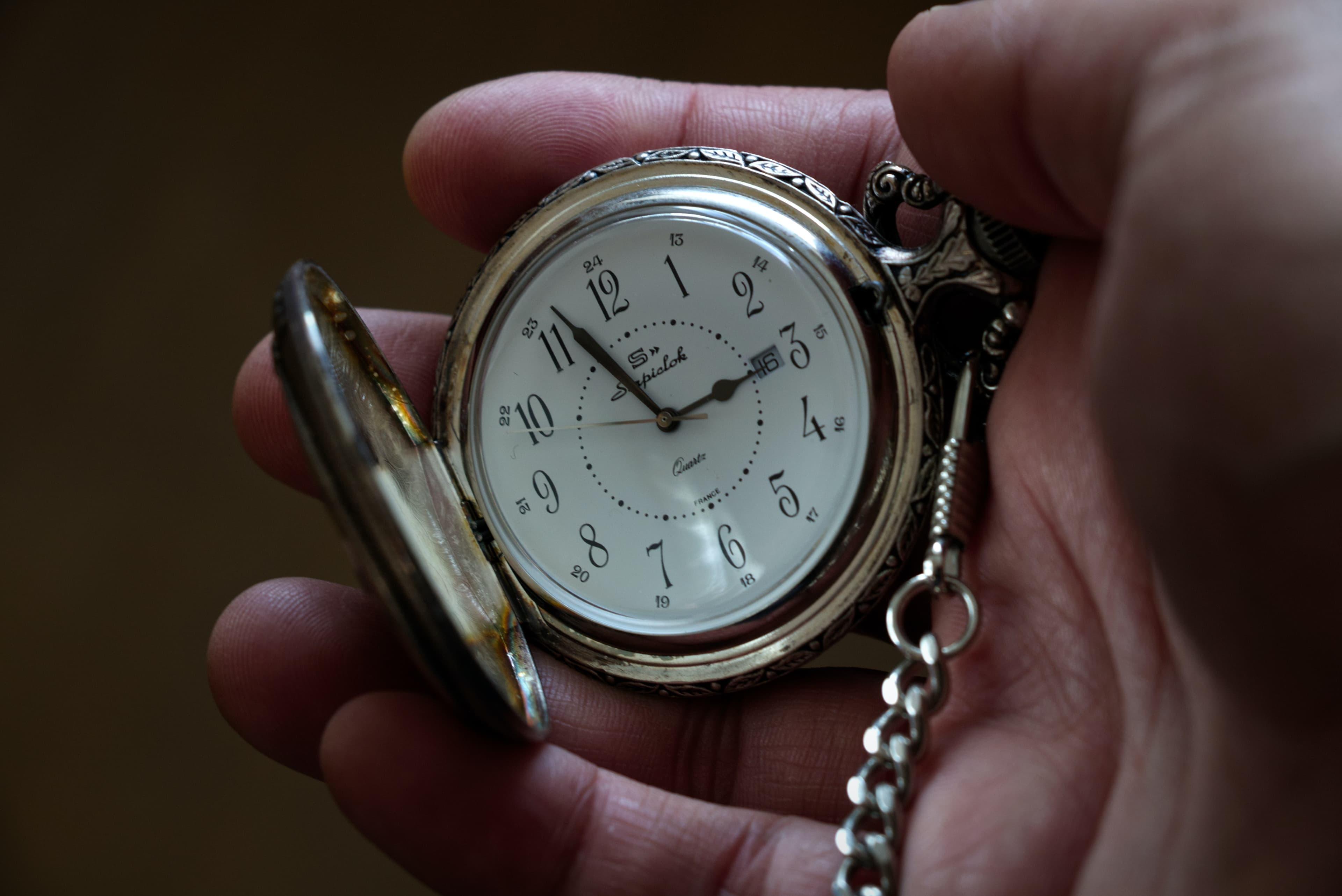 a hand holding a pocket watch